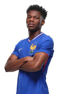 a man with his arms crossed standing in front of a white background wearing a blue shirt