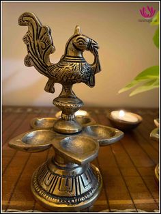 a metal rooster figurine sitting on top of a wooden table next to candles