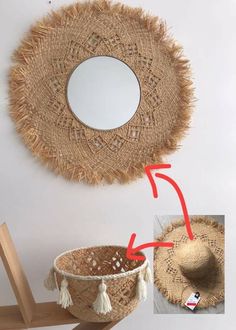 a hat hanging on the wall next to a basket with tassels and a mirror