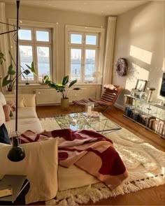 a living room filled with lots of furniture next to a large window covered in blankets