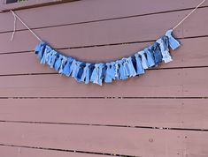 a blue cloth hanging from a clothes line on the side of a wooden wall with string attached to it