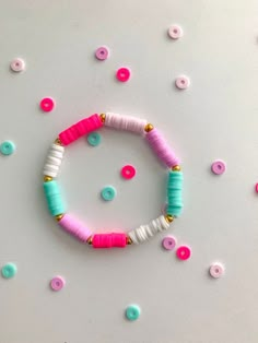 a pink and blue bracelet with white beads on it, surrounded by confetti sprinkles