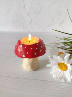 a red candle sitting on top of a white table next to a vase with flowers