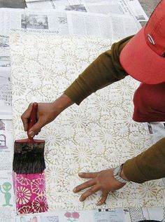 a person is painting on newspaper with a brush and paintbrush in their hand,