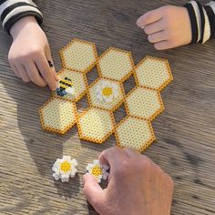 two people playing with bees and daisies on a wooden table