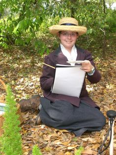 a woman sitting on the ground holding a piece of paper and wearing a straw hat