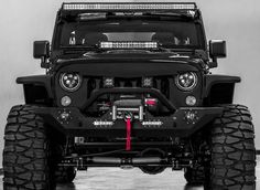 the front end of a black jeep with its lights on and four wheel drive tires