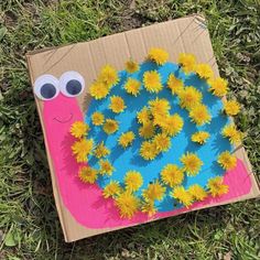 a cardboard box with flowers in the shape of a snail on it and eyes painted on top