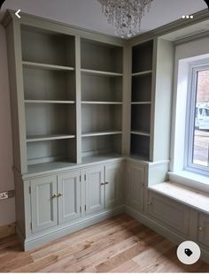 an empty room with built in bookcases and a chandelier