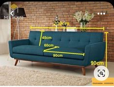 a blue couch sitting on top of a rug next to a brick wall with measurements