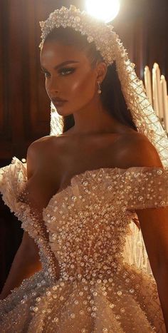 a woman in a wedding dress with pearls on her head and veil over her shoulder