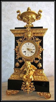 an ornate gold and black clock with cherubs on the sides, sitting on a table