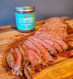 sliced meat on a cutting board next to a jar of nut butter