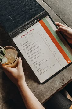 a person sitting at a table with a drink and menu in front of them on a clipboard