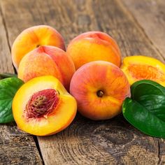 several peaches with leaves on a wooden table