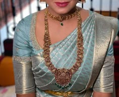 a woman in a blue and gold sari with jewelry on her neck is posing for the camera