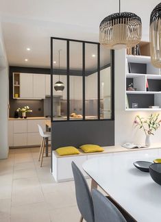 a modern kitchen with white cabinets and yellow pillows on the countertop, along with gray chairs