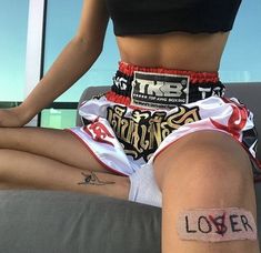 a woman sitting on top of a couch with her legs crossed and tattoos on her leg