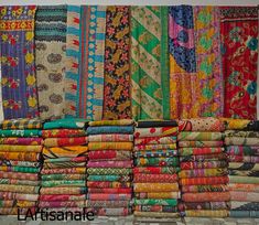 many different colored fabrics are stacked on top of each other in front of a wall