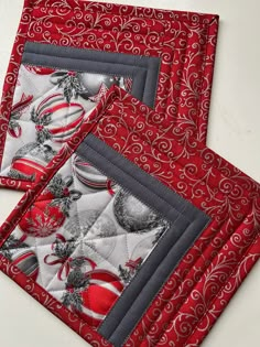 two red and white placemats with christmas decorations on them, one is folded to the side