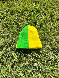 a yellow and green knitted hat laying on the grass