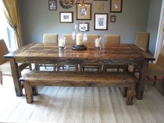 a dining room table with two benches and pictures on the wall