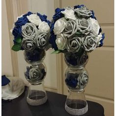 two clear vases with blue and white flowers in them on top of a table