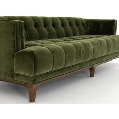 a green velvet couch with wooden legs on an isolated white flooring area, facing the camera