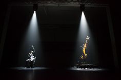 two dancers are performing on stage in the dark