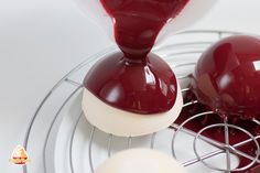 two red and white desserts sitting on top of a metal rack with sauce pouring over them