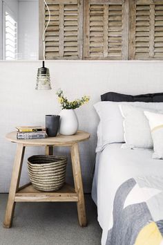 a bed room with a neatly made bed and a basket on the side table next to it