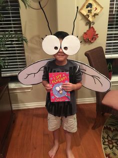 a young boy holding a book in front of his face with two large eyes on it