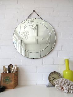 a mirror hanging on the wall next to a clock and other items in front of it