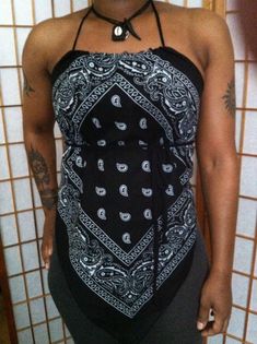 a woman standing in front of a tiled wall wearing a black and white bandana