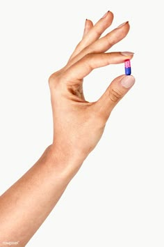 a person's hand holding a small pill in the middle of their left hand