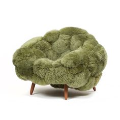 a green chair sitting on top of a wooden leg rest with fur covering it's back