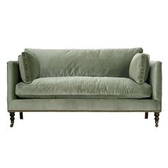 a green velvet couch with two pillows on the back and one arm upholstered