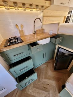 a small kitchen with an oven, sink and stove top in it's corner