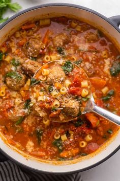 a ladle full of soup with meatballs and vegetables