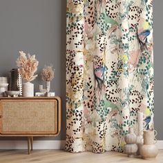 a curtain with birds and flowers on it in front of a tv stand next to a wall