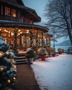 a house with christmas lights on the front porch and trees in the snow around it