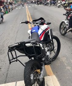 the motorcycle is parked on the side of the road with other motorcycles in the background