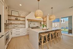 a kitchen with white cabinets and wooden stools in front of an open floor plan