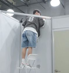 a man standing on a stepladder in front of a mirror with his head down