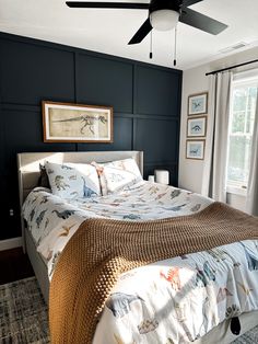 a bedroom with a bed, ceiling fan and two pictures on the wall above it