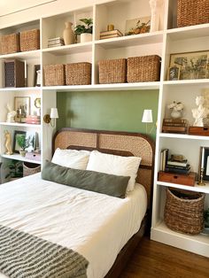 a bed sitting in a bedroom next to a book shelf filled with books and baskets