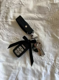 two keys tied to each other on top of a white sheet with black ribbon around them