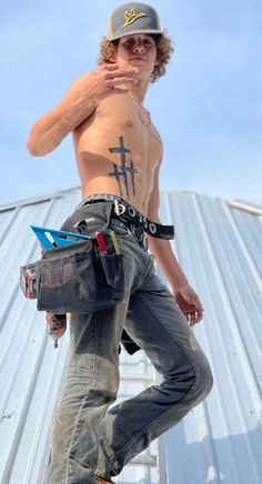 a shirtless man standing on top of a skateboard wearing jeans and a hat