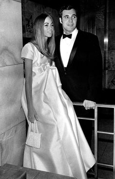 a man in a tuxedo standing next to a woman in a white dress