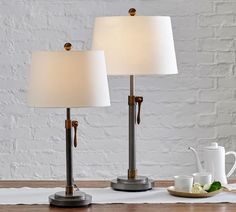 two lamps sitting on top of a wooden table next to a cup and saucer